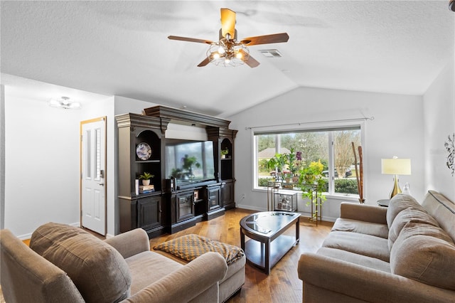 living room featuring a ceiling fan, wood finished floors, visible vents, baseboards, and vaulted ceiling