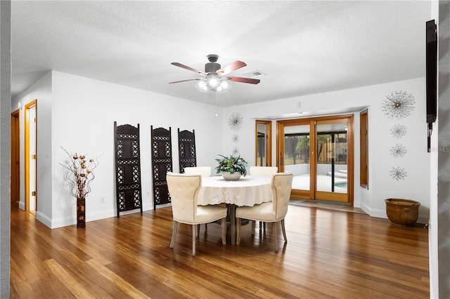 dining space with a ceiling fan, wood finished floors, visible vents, baseboards, and a textured ceiling