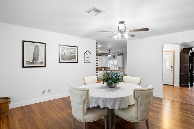 dining space with visible vents, baseboards, a textured ceiling, and dark wood-style floors