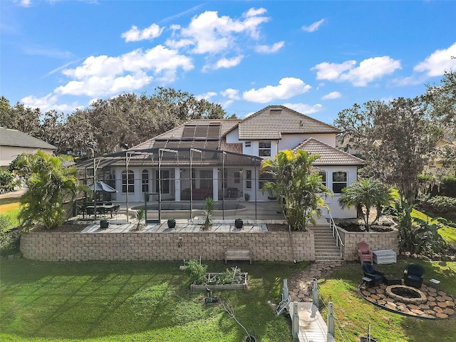 rear view of property featuring a yard, a lanai, a pool, a fire pit, and a patio