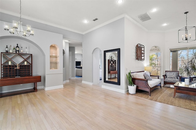 interior space with a notable chandelier, ornamental molding, and light hardwood / wood-style floors