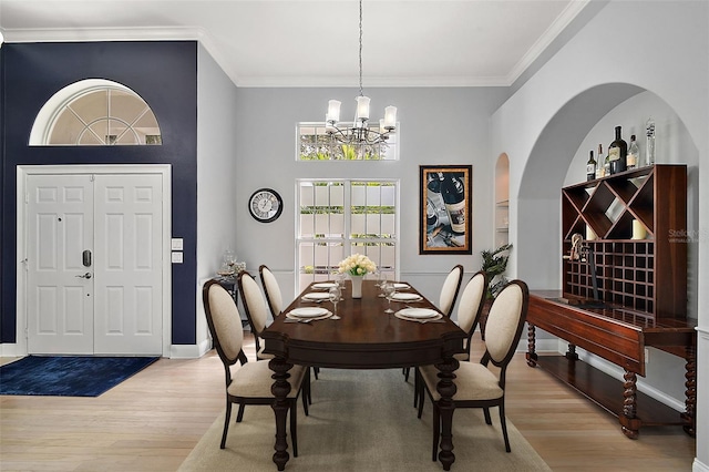 dining room featuring crown molding, a notable chandelier, and light wood-type flooring