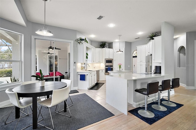 kitchen featuring white cabinetry, sink, pendant lighting, and built in appliances