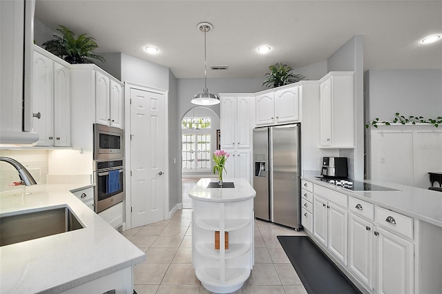 kitchen with appliances with stainless steel finishes, decorative light fixtures, sink, white cabinets, and a center island