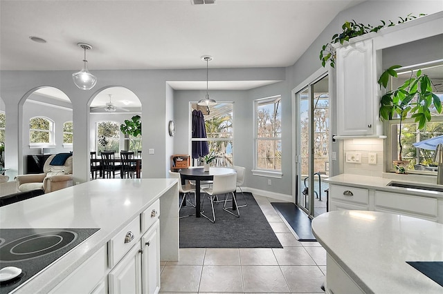 kitchen with cooktop, hanging light fixtures, light tile patterned floors, white cabinets, and backsplash