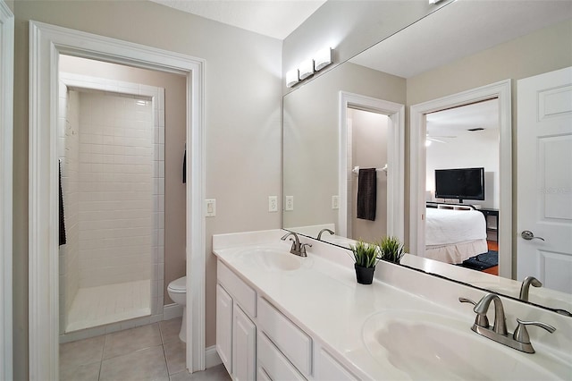 bathroom featuring a tile shower, vanity, tile patterned floors, and toilet