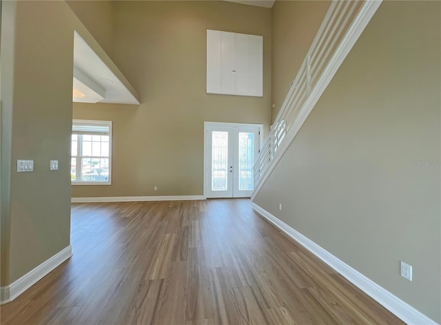 entrance foyer with a towering ceiling, french doors, and light wood-type flooring