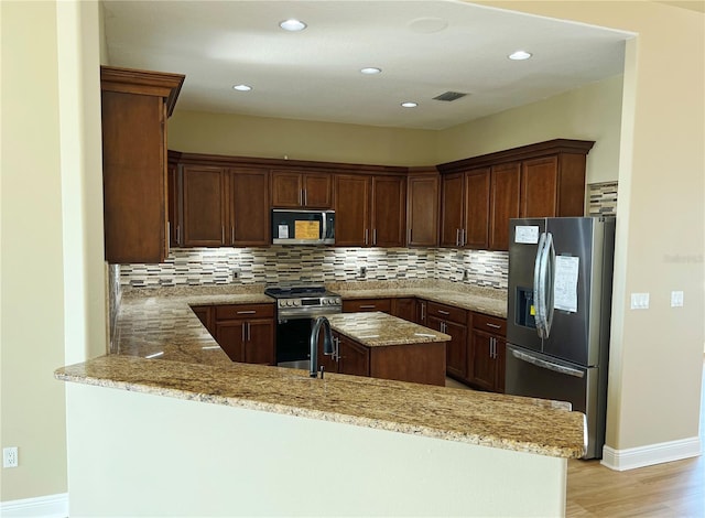 kitchen with light stone counters, stainless steel appliances, and kitchen peninsula