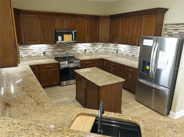 kitchen featuring stainless steel appliances, light stone countertops, sink, and decorative backsplash