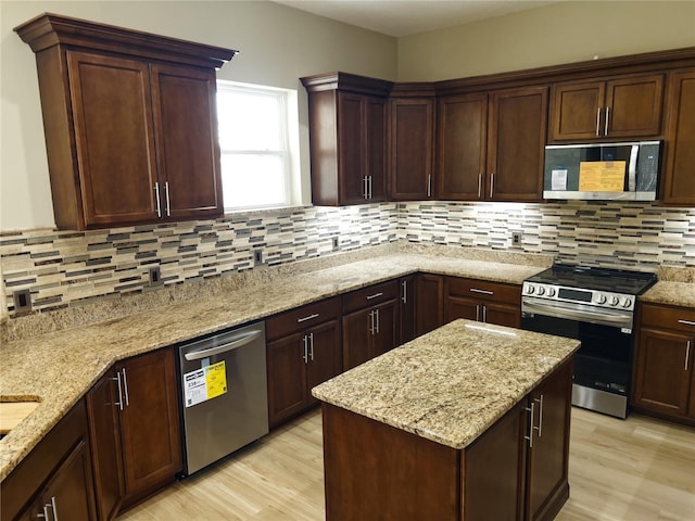 kitchen with light hardwood / wood-style flooring, light stone countertops, and appliances with stainless steel finishes