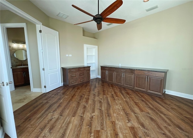 unfurnished bedroom with dark wood-type flooring, ensuite bath, ceiling fan, and sink