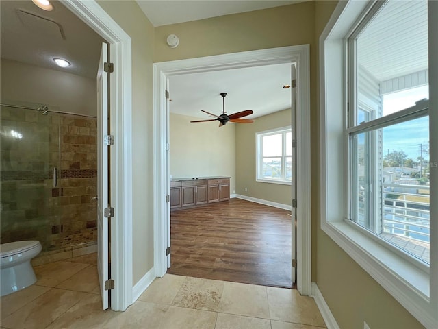 interior space featuring ceiling fan, an enclosed shower, tile patterned floors, and toilet