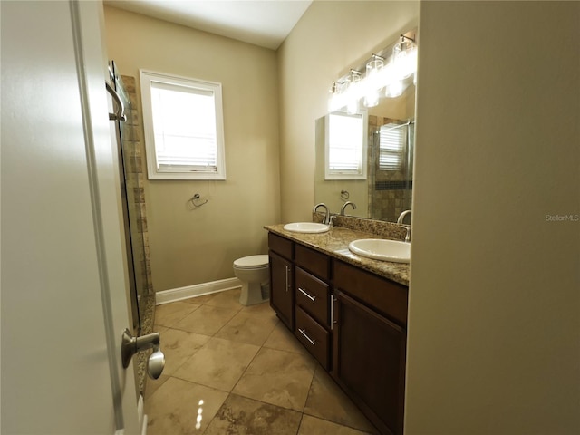 bathroom with tile patterned flooring, vanity, toilet, and a healthy amount of sunlight