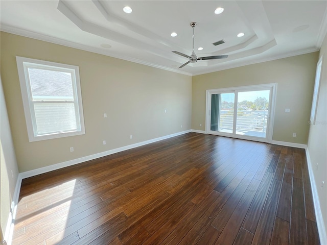 spare room with a tray ceiling, dark wood-type flooring, ornamental molding, and ceiling fan