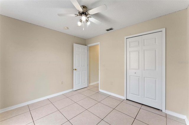 unfurnished bedroom featuring ceiling fan, a closet, and light tile patterned floors