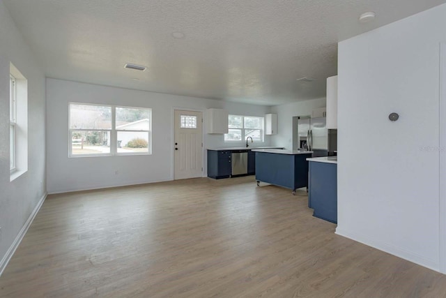 kitchen featuring white cabinetry, blue cabinetry, stainless steel appliances, and a kitchen island