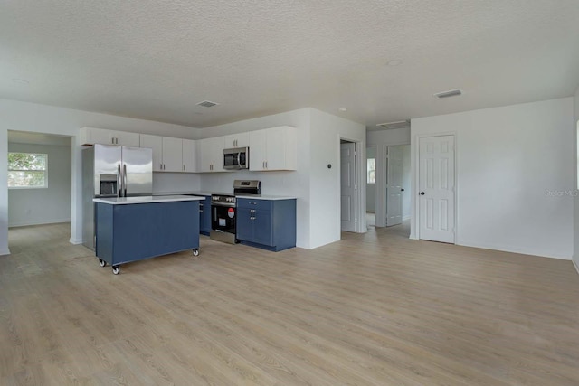 kitchen with blue cabinets, white cabinetry, light hardwood / wood-style flooring, a kitchen island, and stainless steel appliances