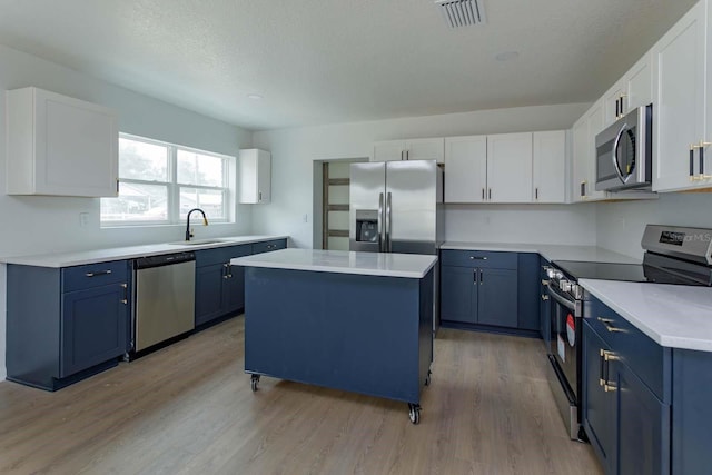 kitchen with blue cabinetry, sink, white cabinetry, a center island, and appliances with stainless steel finishes