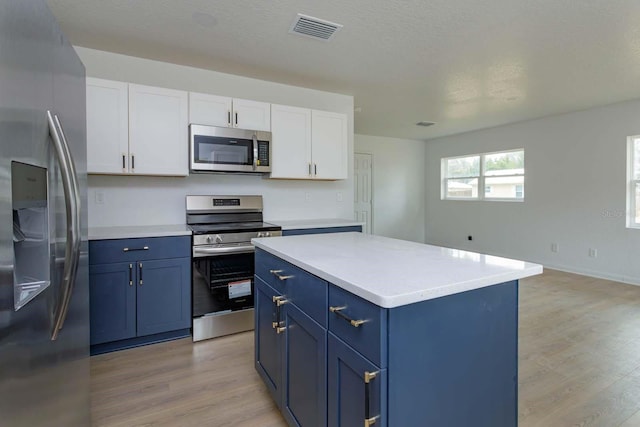 kitchen featuring blue cabinets, white cabinetry, a center island, stainless steel appliances, and light wood-type flooring