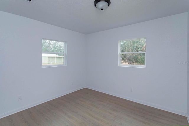 empty room featuring a textured ceiling and light hardwood / wood-style floors