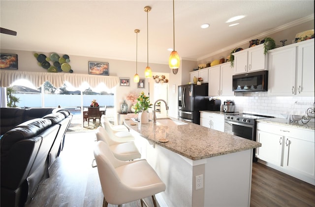 kitchen with sink, appliances with stainless steel finishes, white cabinetry, light stone countertops, and decorative light fixtures