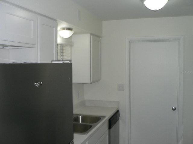 kitchen featuring black refrigerator, sink, white cabinetry, and stainless steel dishwasher