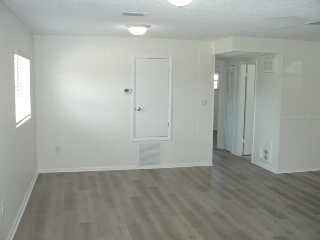 empty room with hardwood / wood-style floors and a textured ceiling