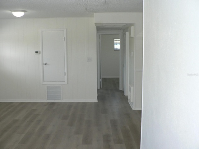 empty room with dark hardwood / wood-style flooring and a textured ceiling