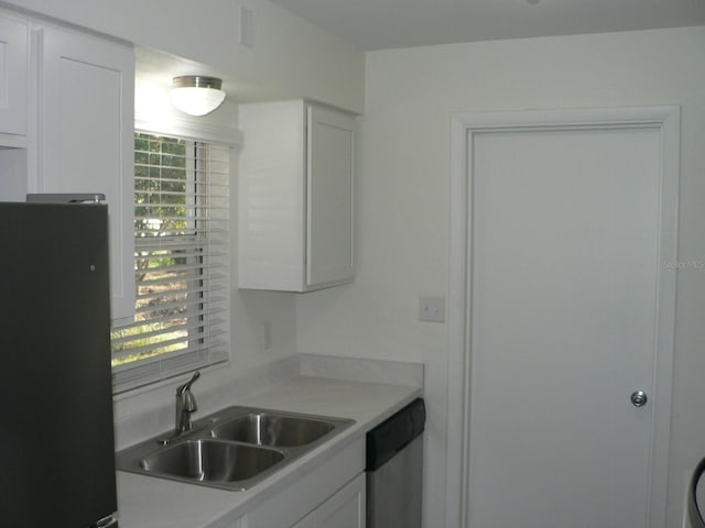 kitchen featuring white cabinetry, stainless steel dishwasher, black refrigerator, and sink