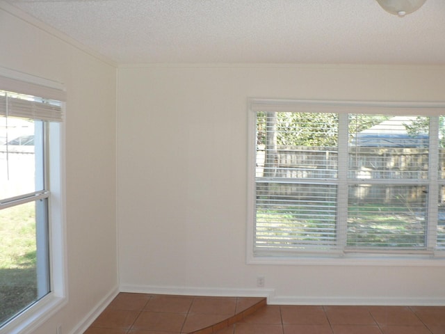 tiled empty room with a textured ceiling