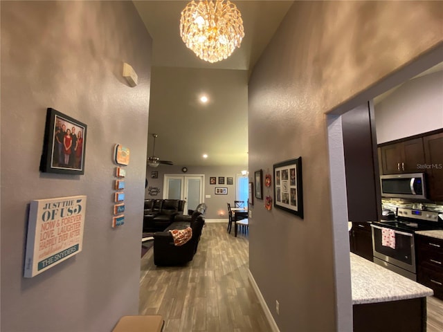 corridor featuring a high ceiling, a chandelier, and light hardwood / wood-style floors