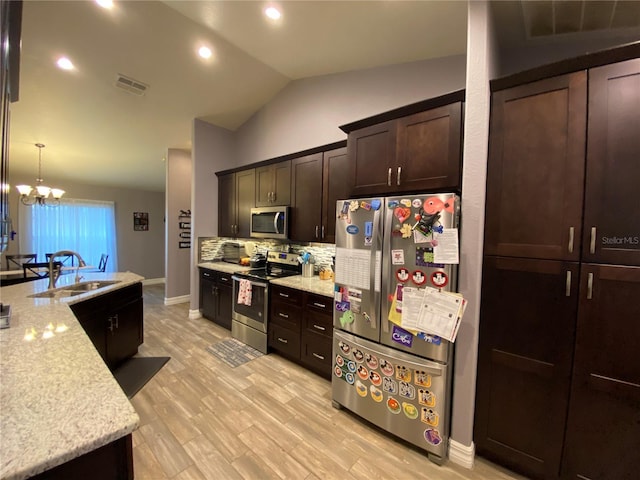 kitchen featuring lofted ceiling, sink, decorative light fixtures, dark brown cabinets, and appliances with stainless steel finishes