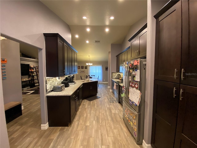 kitchen featuring lofted ceiling, dark brown cabinets, hanging light fixtures, light hardwood / wood-style flooring, and stainless steel appliances