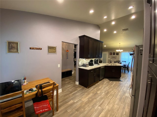 kitchen featuring an inviting chandelier, decorative light fixtures, appliances with stainless steel finishes, kitchen peninsula, and light hardwood / wood-style floors