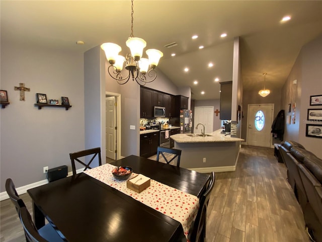 dining area featuring vaulted ceiling, sink, hardwood / wood-style floors, and a notable chandelier