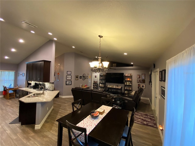 dining area featuring vaulted ceiling, dark hardwood / wood-style floors, sink, and a notable chandelier