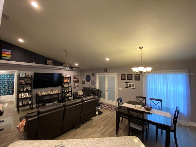 living room with hardwood / wood-style flooring, lofted ceiling, and ceiling fan with notable chandelier