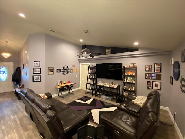 home theater room featuring ceiling fan with notable chandelier, vaulted ceiling, and wood-type flooring