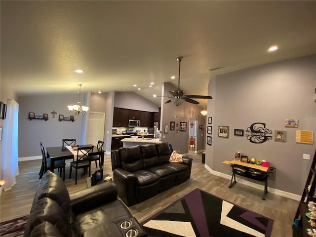 living room featuring hardwood / wood-style flooring, lofted ceiling, and ceiling fan with notable chandelier