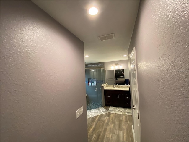 bathroom with hardwood / wood-style flooring, vanity, and a shower with door