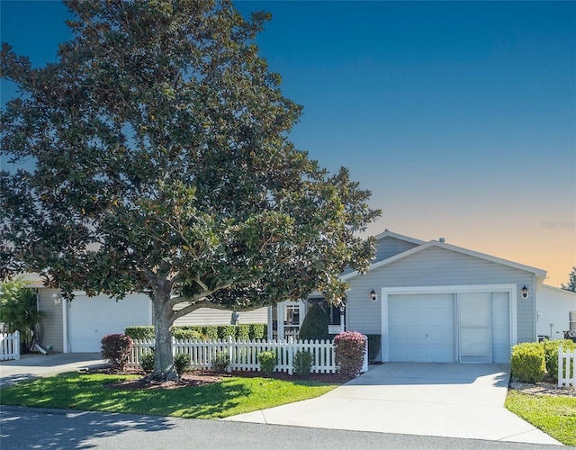 view of front of property with concrete driveway, an attached garage, and a fenced front yard