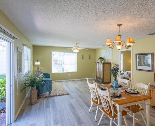 dining area with light wood finished floors, visible vents, a textured ceiling, and baseboards