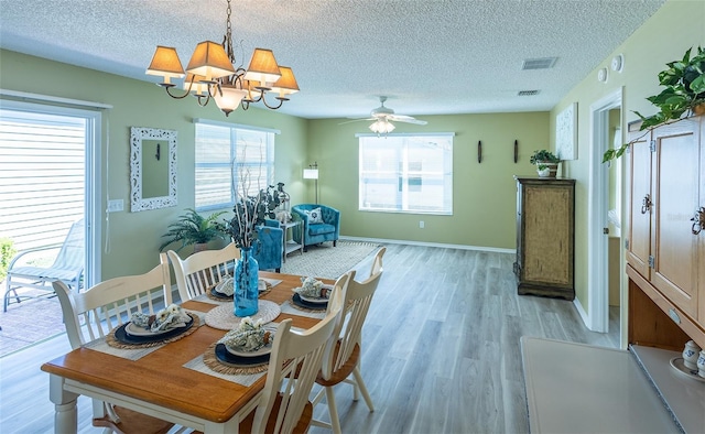 dining area with visible vents, ceiling fan with notable chandelier, a textured ceiling, light wood finished floors, and baseboards