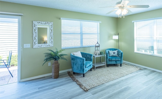 sitting room with ceiling fan, baseboards, a textured ceiling, and wood finished floors