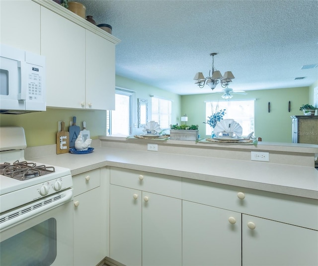 kitchen featuring an inviting chandelier, white appliances, light countertops, and a textured ceiling