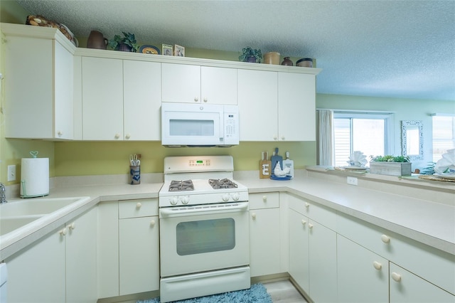 kitchen featuring a sink, a textured ceiling, white appliances, white cabinets, and light countertops