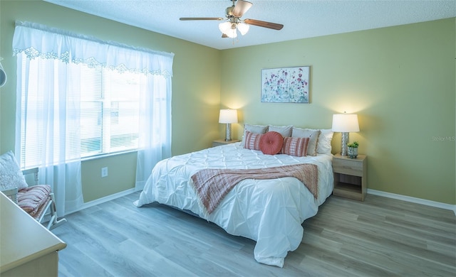 bedroom featuring baseboards, a textured ceiling, and wood finished floors