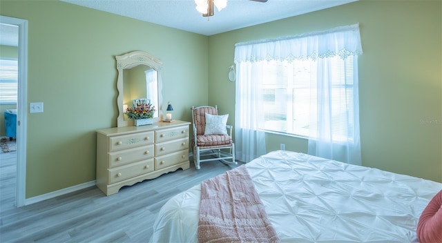 bedroom featuring baseboards, a textured ceiling, light wood-style flooring, and a ceiling fan