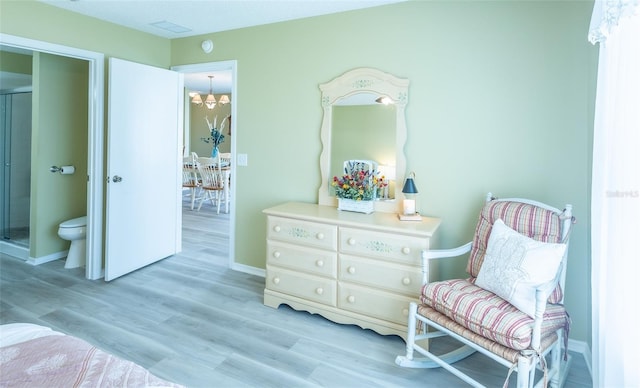 sitting room with light wood-style flooring, a notable chandelier, and baseboards