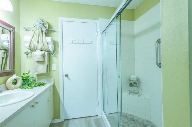 full bath with vanity, wood finished floors, and a stall shower